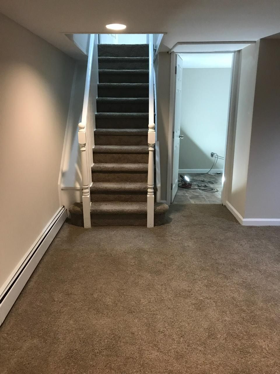 Staircase leading up to an open doorway. Beige carpet, white banister, and off-white walls.