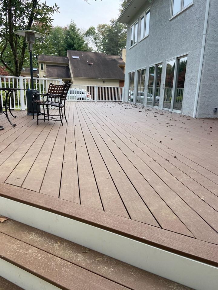 Wooden deck with outdoor furniture, next to a light-colored stucco house.