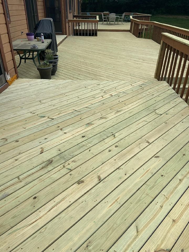 Wooden deck with railing, extending from a house.