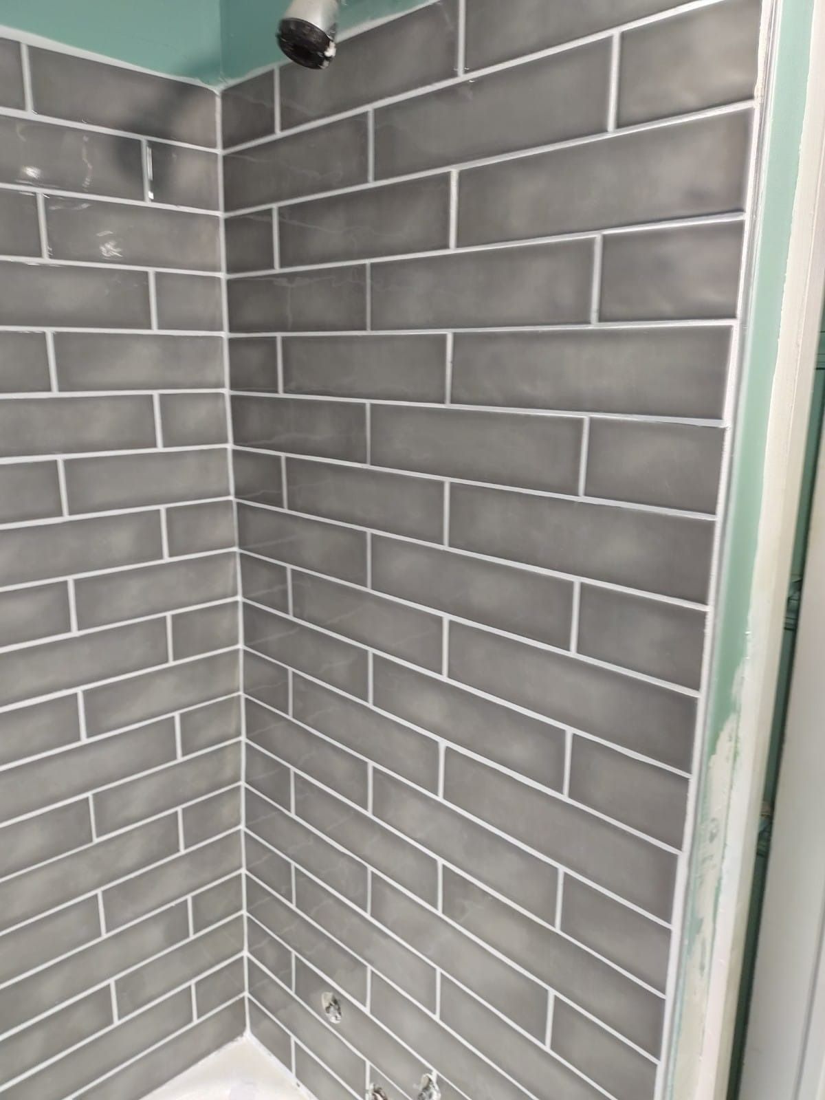 Gray tiled shower with silver grout; partially completed installation.