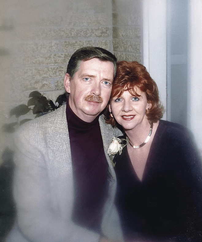 Two people in formal attire smiling and posing closely together indoors.