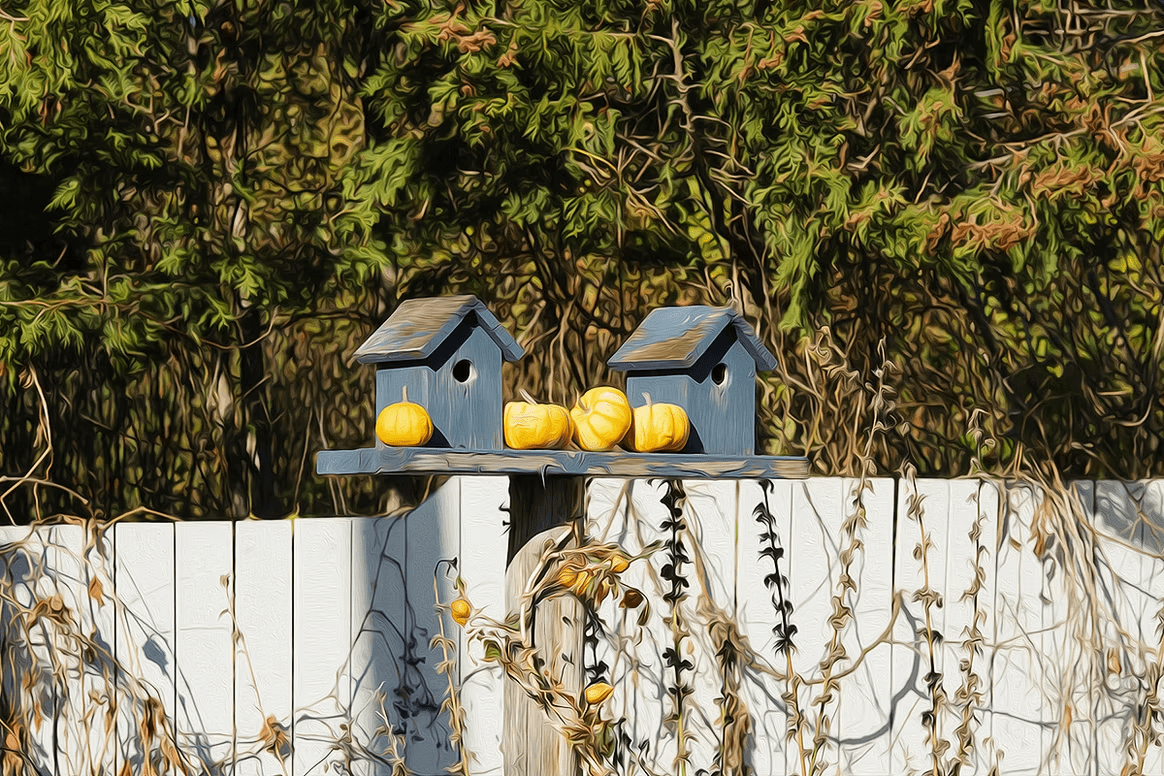 Two blue birdhouses on a white fence with yellow lemons, backed by dense green foliage