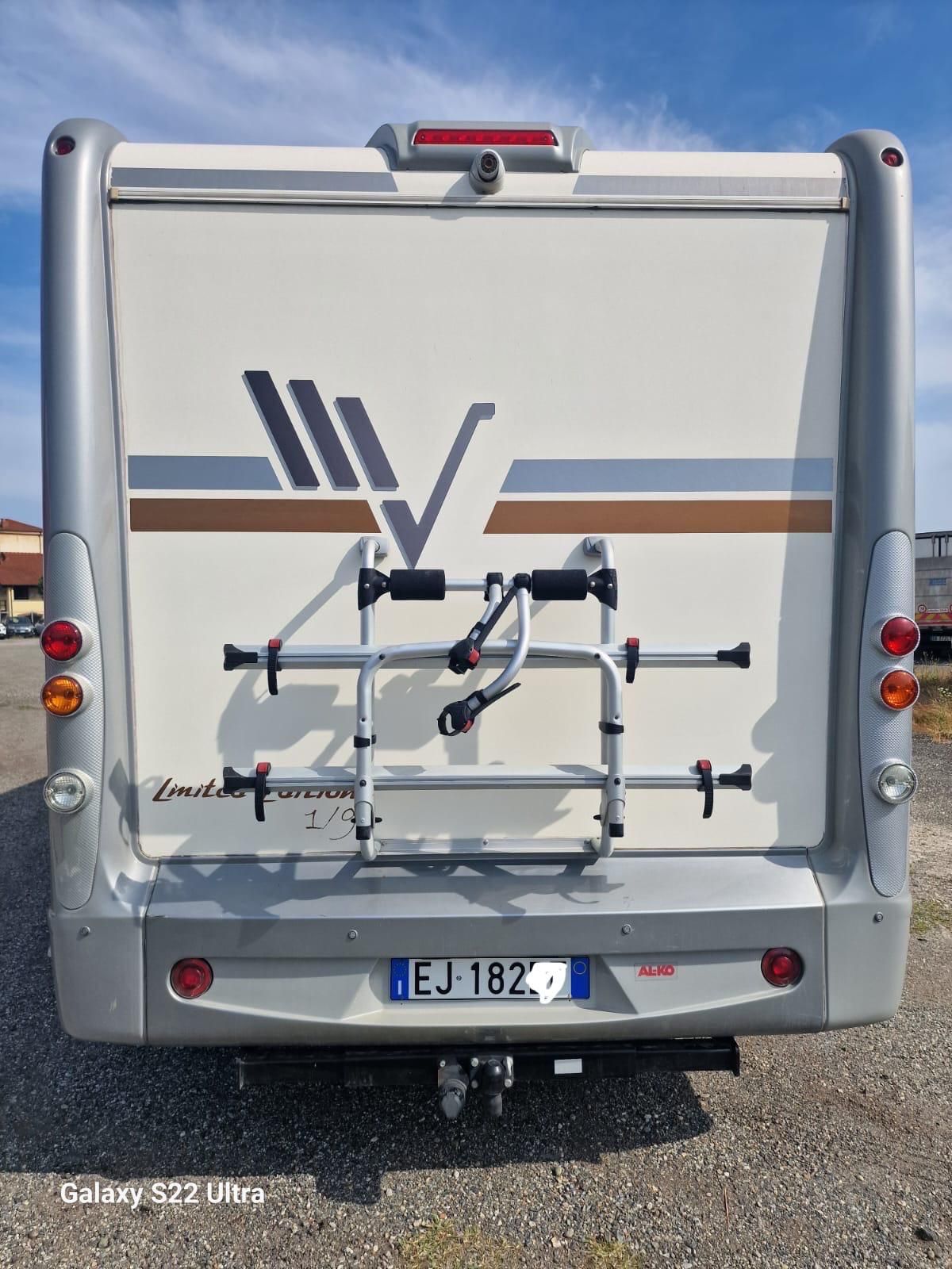 Vista posteriore di un camper bianco e grigio con portabiciclette; targa