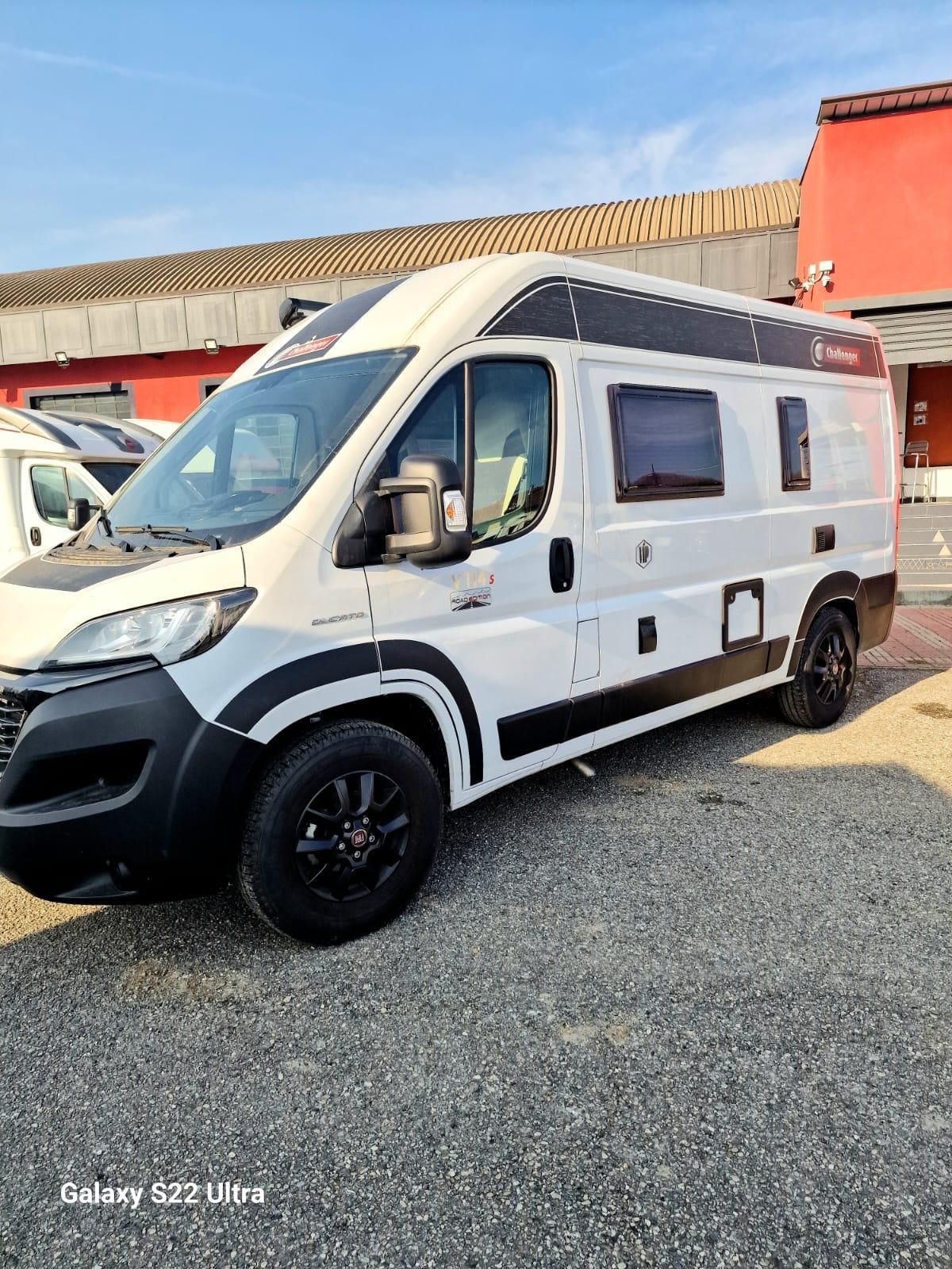 Camper bianco con dettagli neri parcheggiato all'esterno.