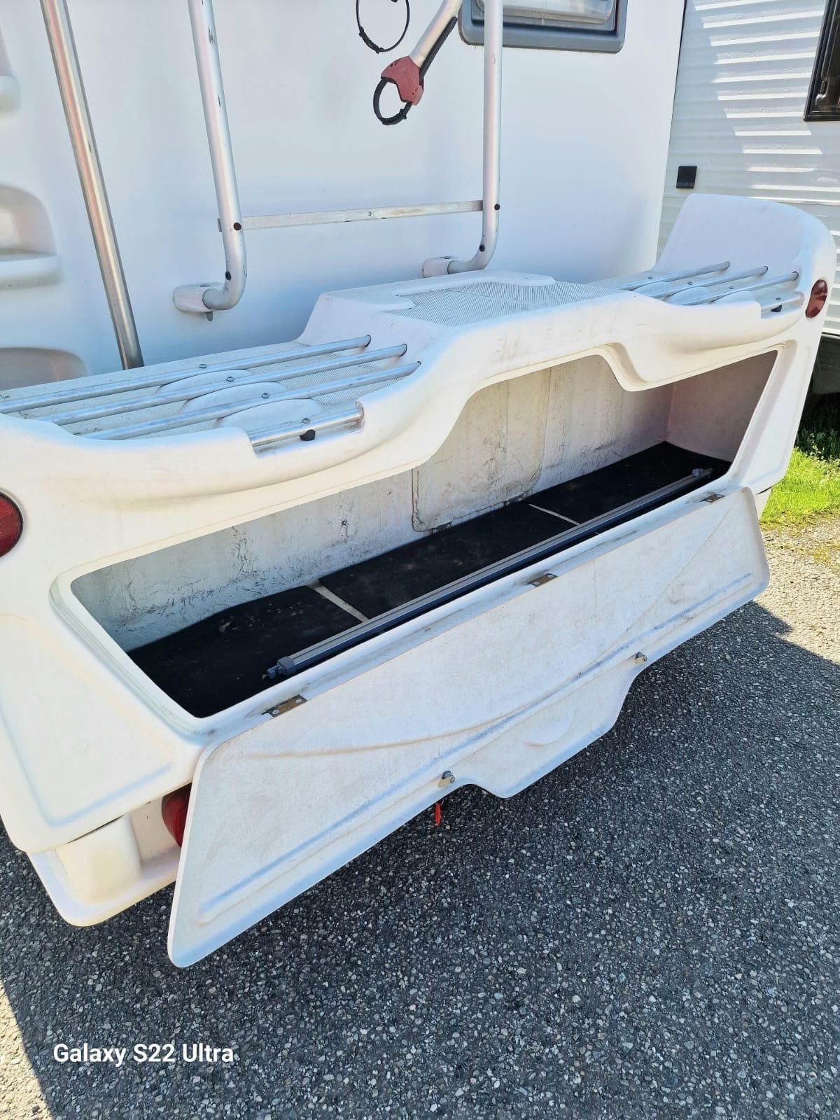 Vano portaoggetti aperto sul retro di un camper bianco, con sportello abbassato.