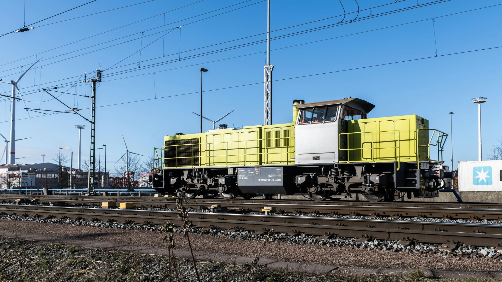 Um trem amarelo e branco está estacionado nos trilhos.
