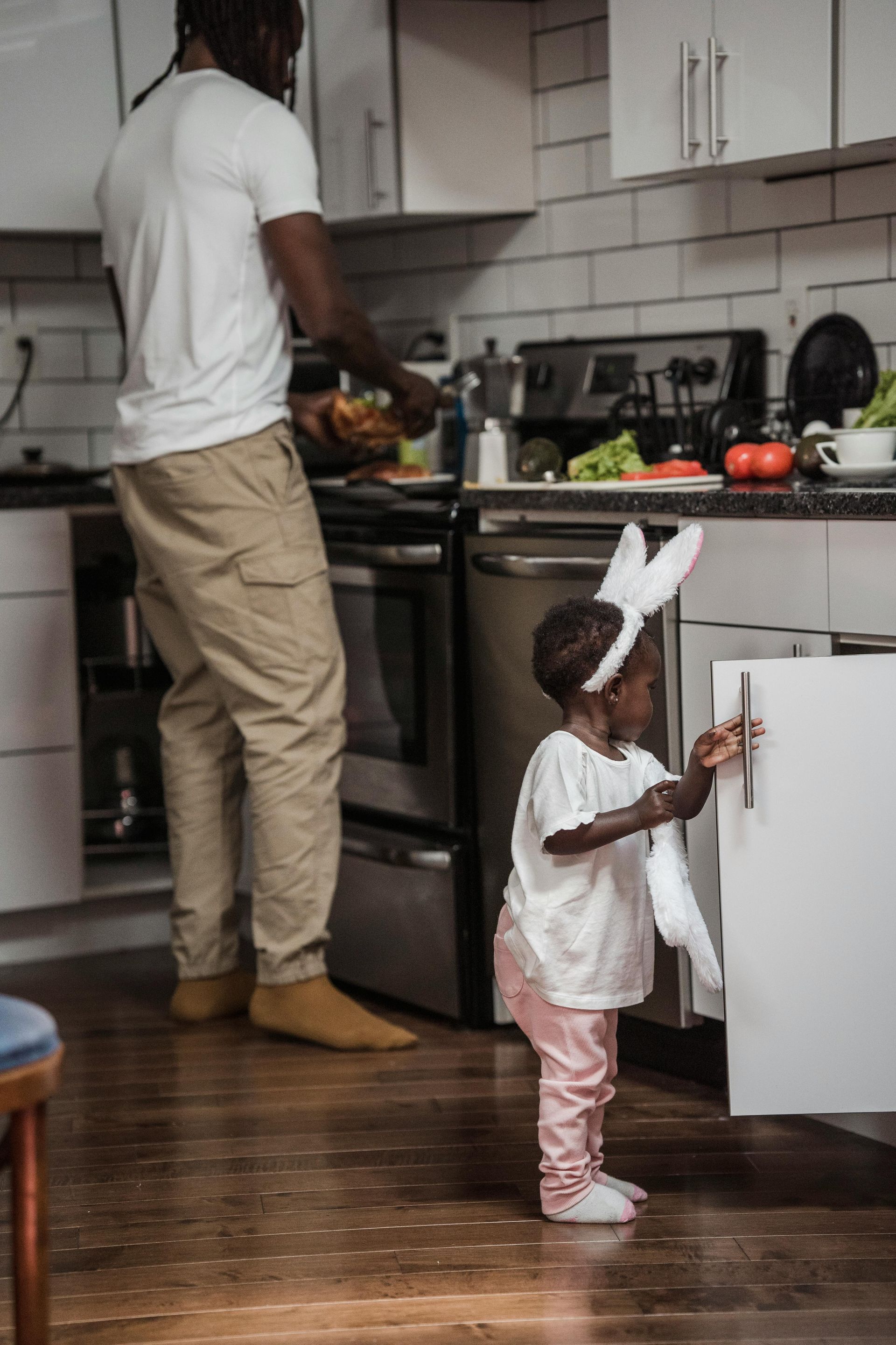 Um homem e uma menina estão em uma cozinha. a menina está vestindo uma fantasia de coelho.