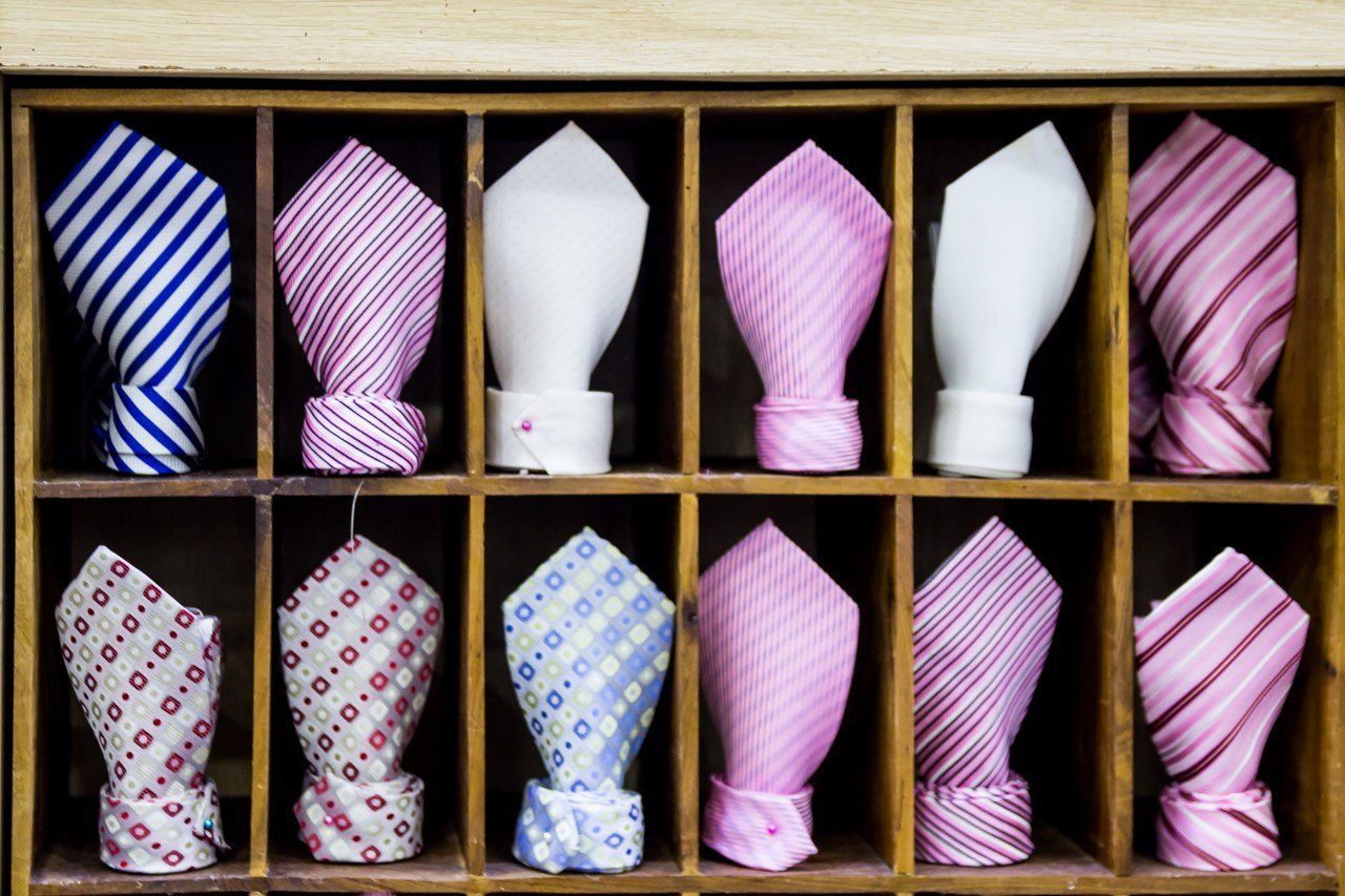 A row of pocket squares are lined up on a shelf