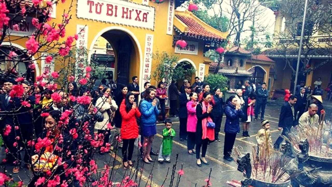 A group of people are standing in front of a building with flowers in front of it.