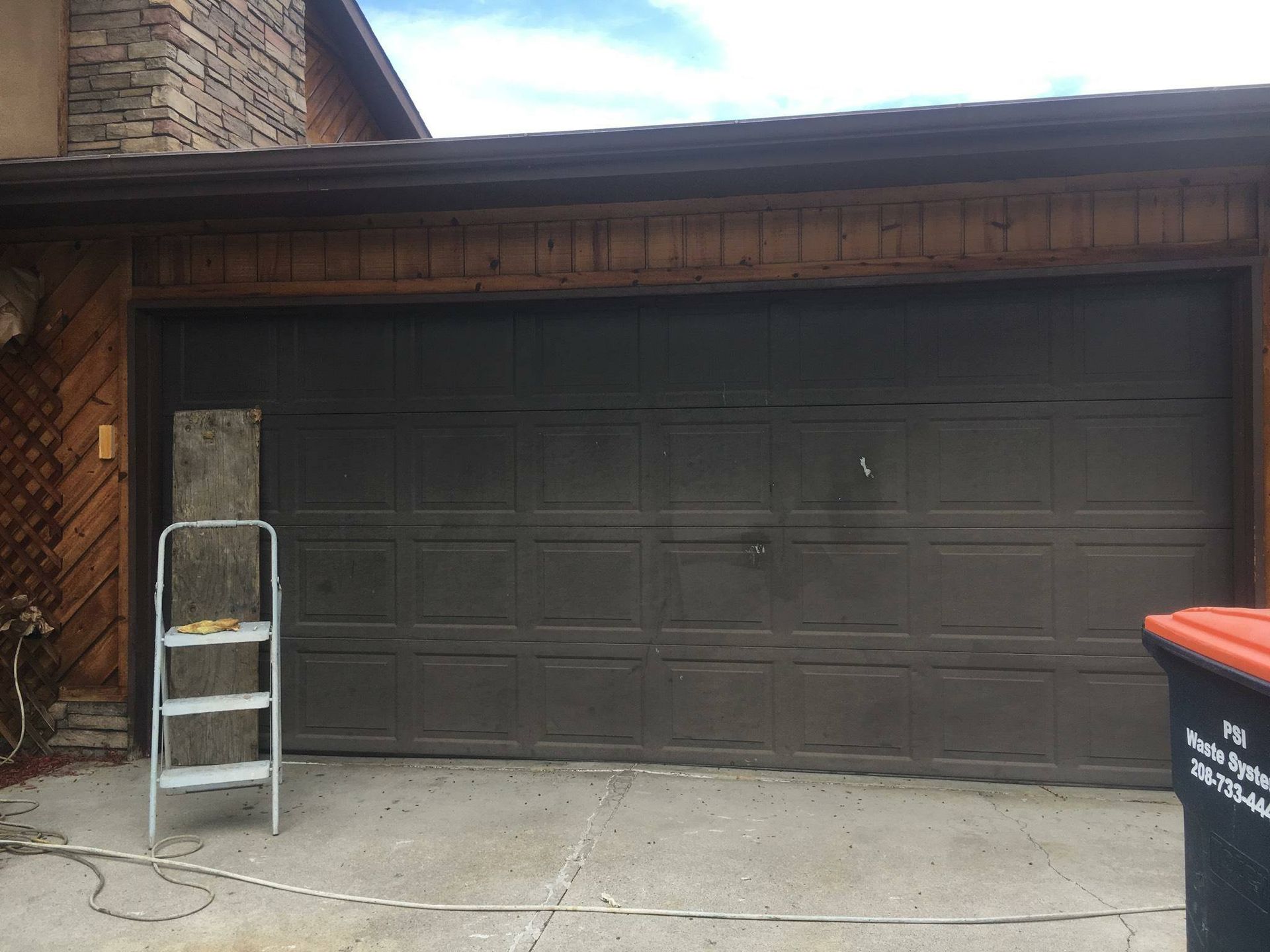 A ladder is sitting in front of a garage door.