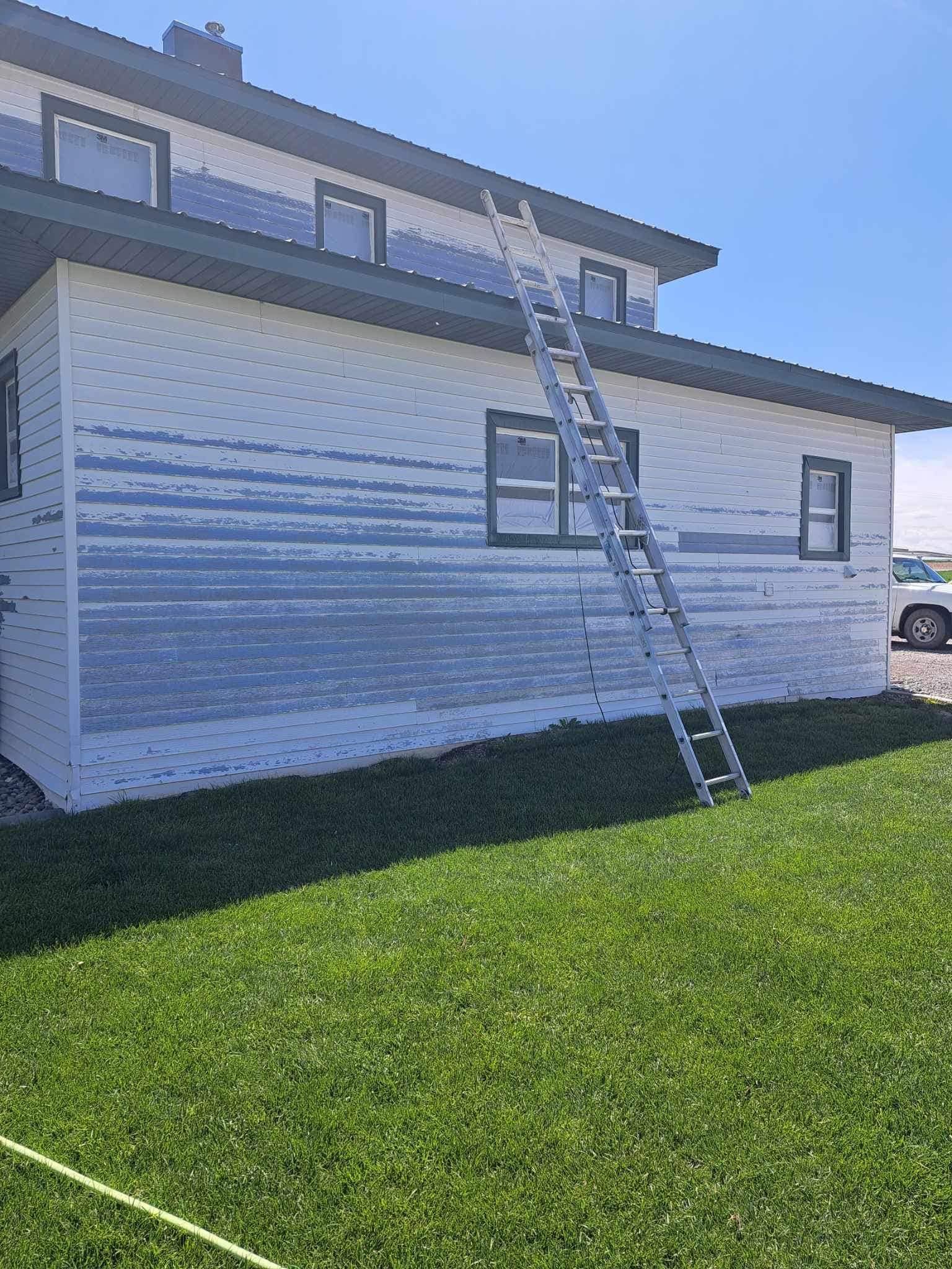 A white house with a ladder on the side of it.