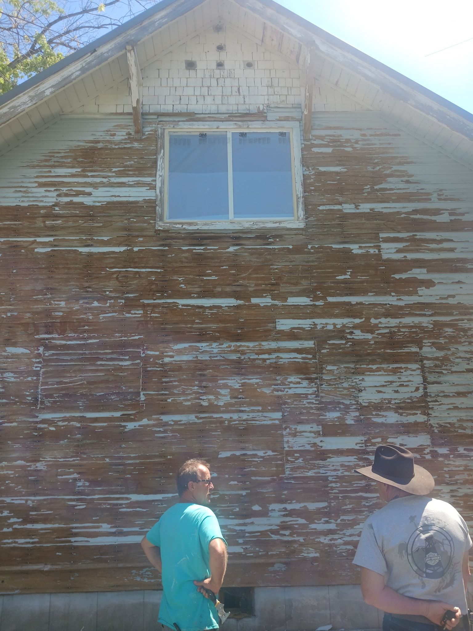 Two men are standing in front of a house with peeling paint