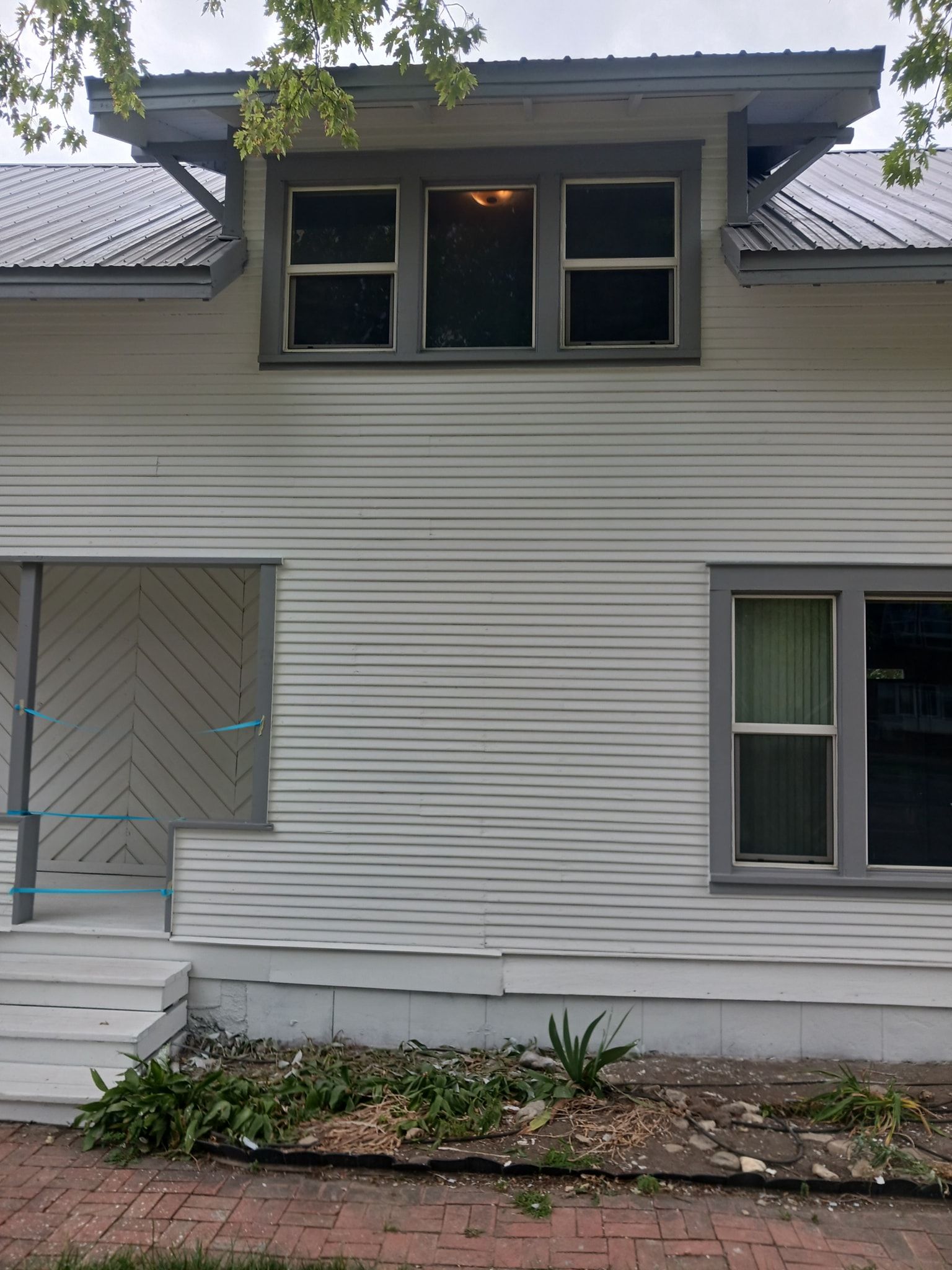 A white house with a metal roof and a lot of windows.