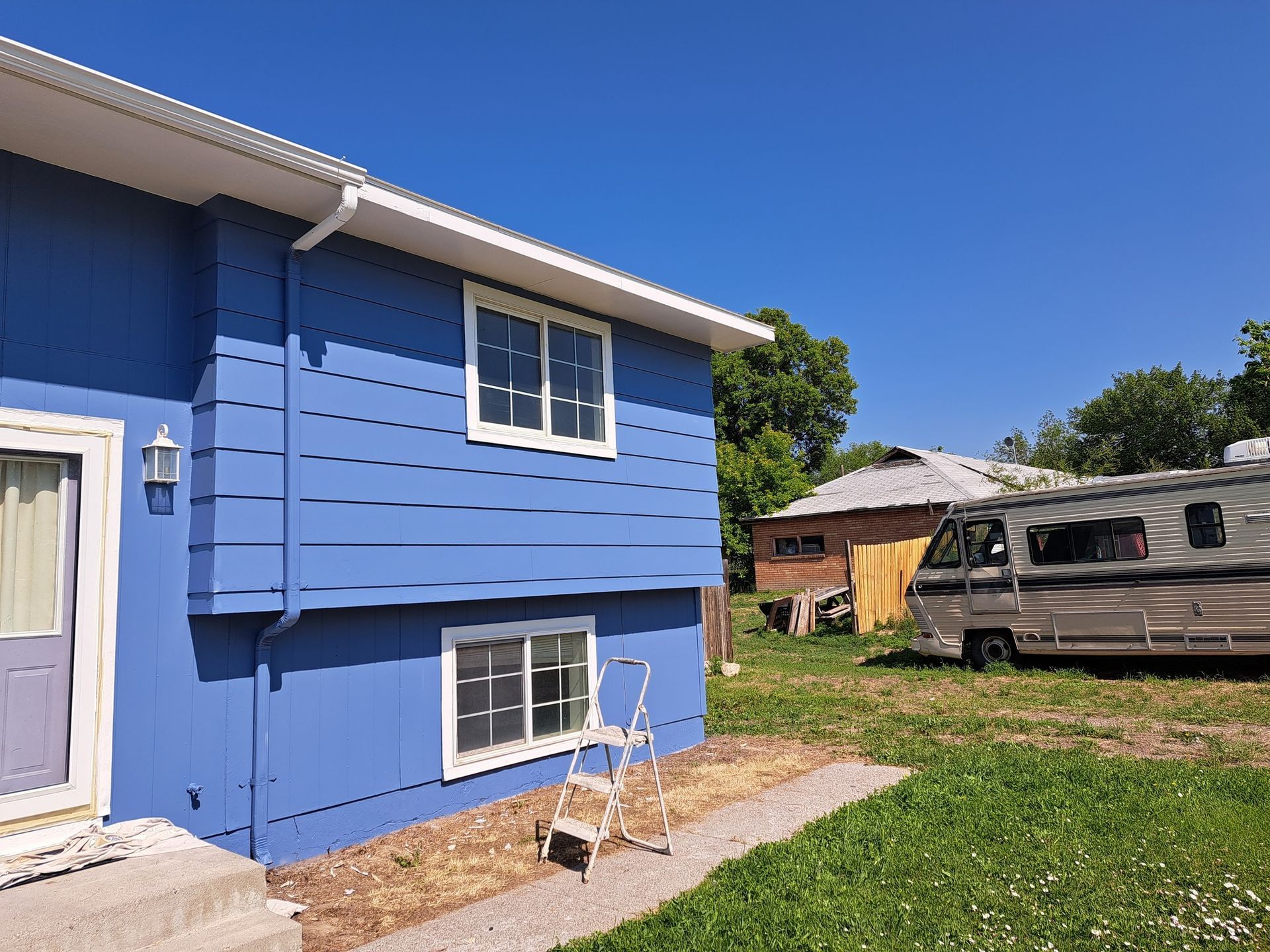 A blue house with a rv parked in front of it