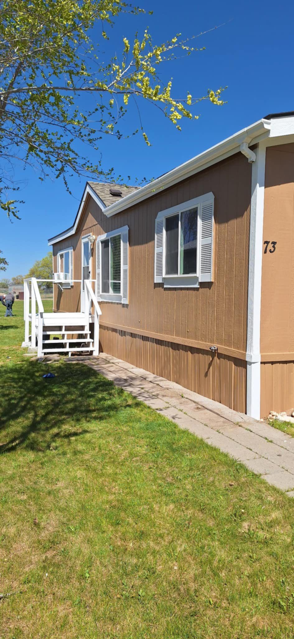 A mobile home with a porch and stairs on a sunny day.