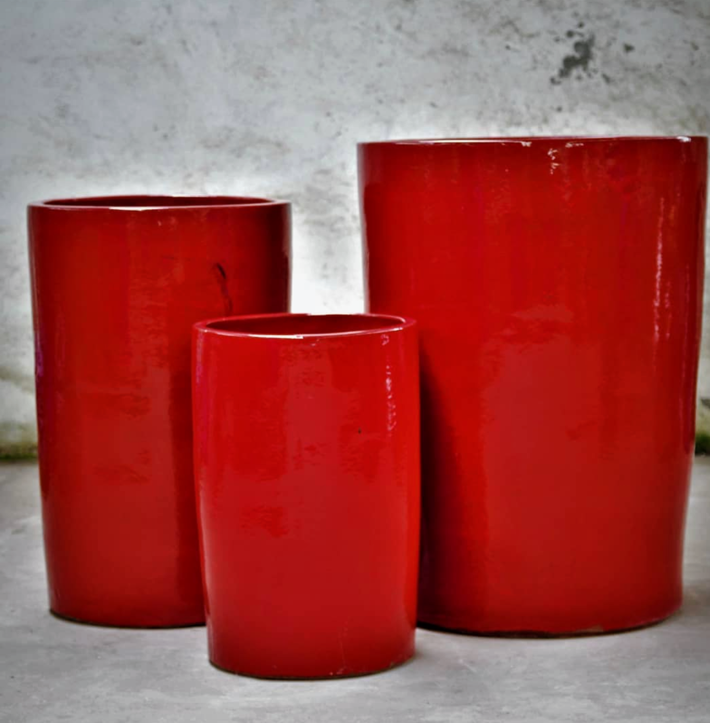 Three red vases are sitting next to each other on a table