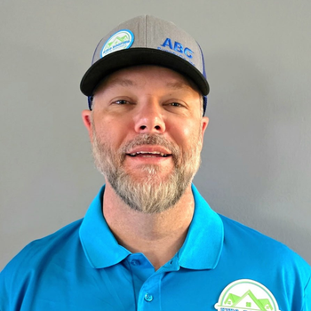 A man with a beard is wearing a hat and a blue shirt.