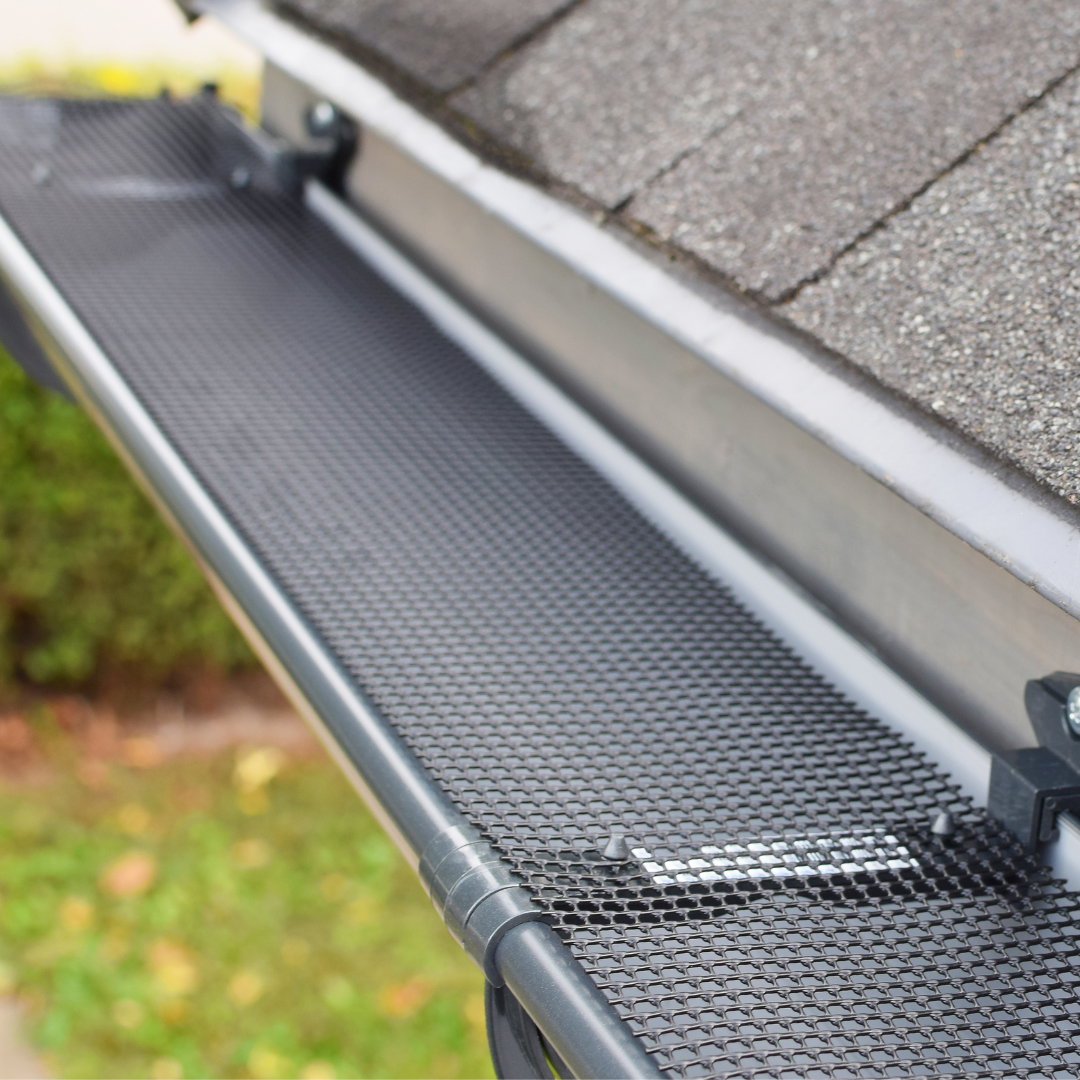 A close up of a gutter with a mesh screen on it.