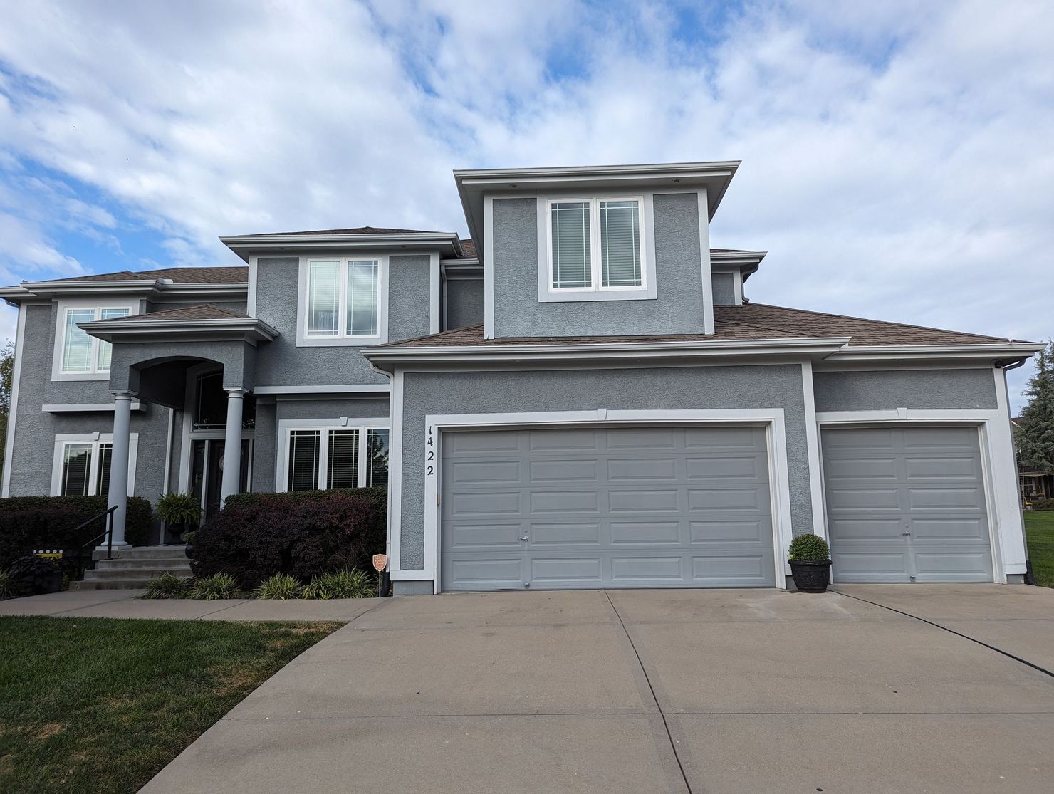 A large gray house with three garage doors and a driveway.
