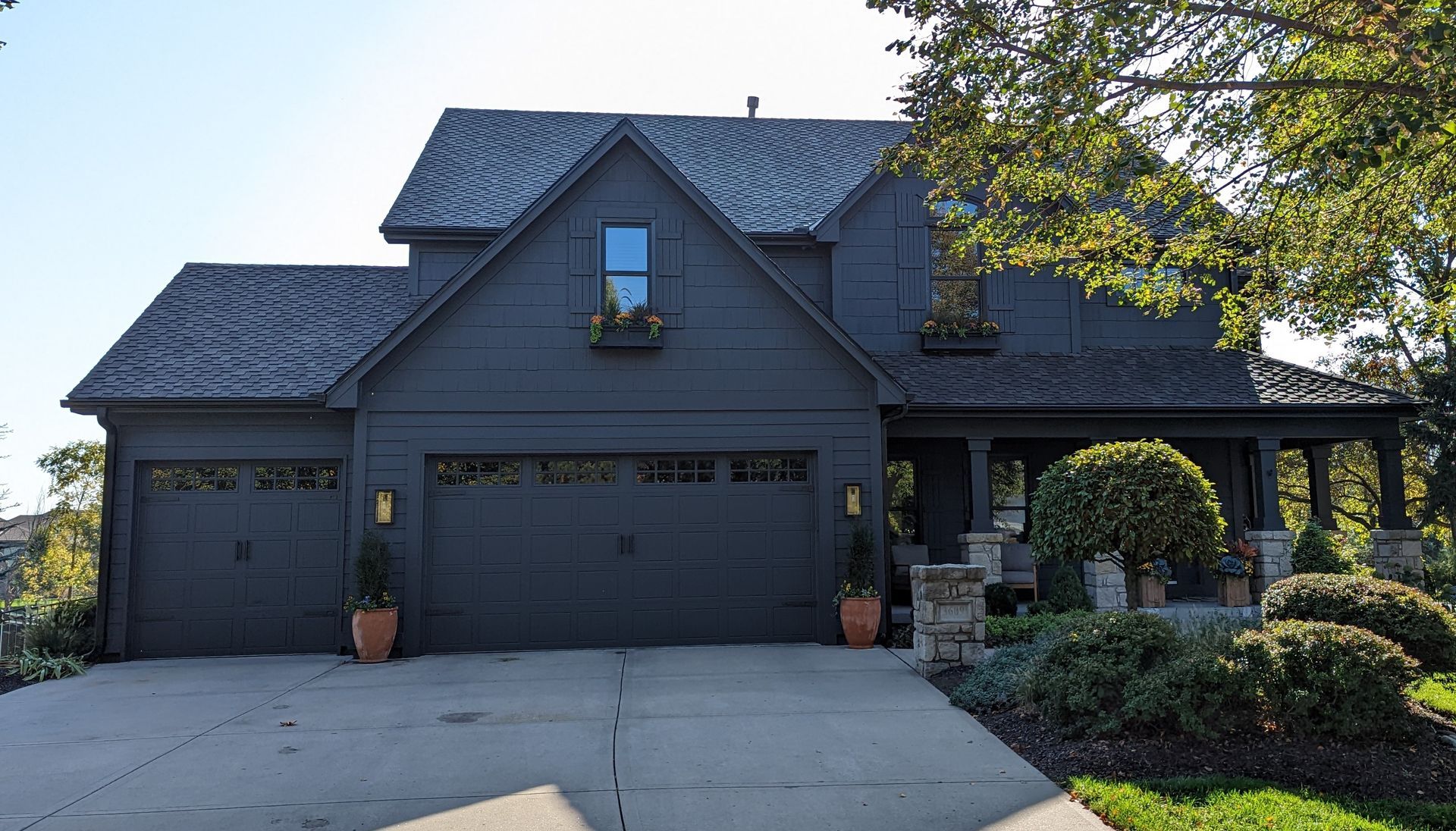 A large black house with a garage and a porch
