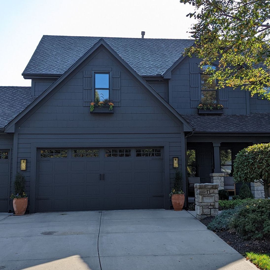 A black house with a gray roof and a black garage door