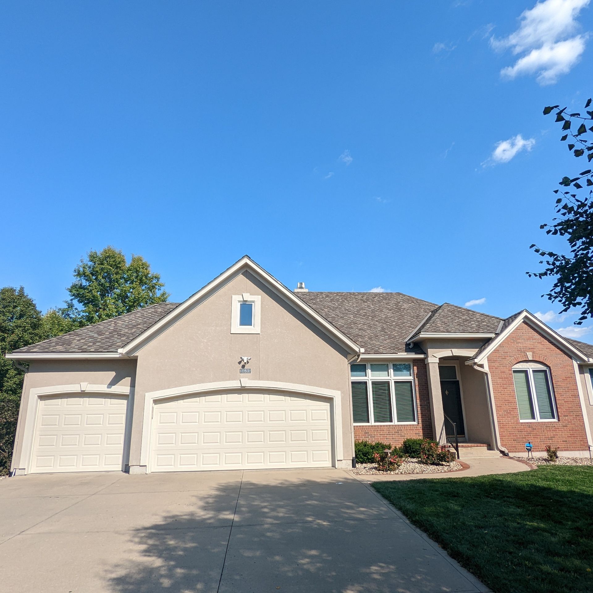 A house with two garage doors and a blue sky in the background