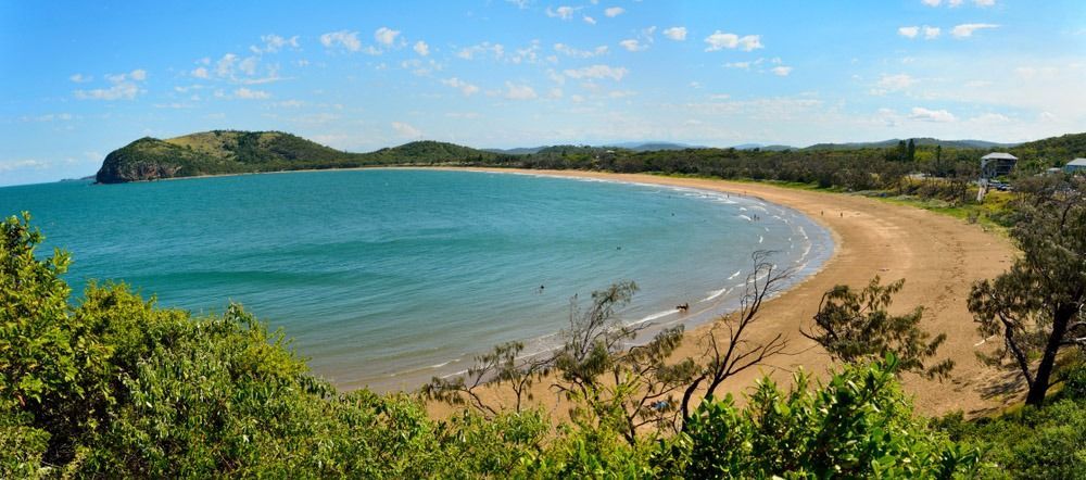 A Large Body Of Water With A Sandy Beach And Trees In The Foreground — Angels for Pets In Capricorn Coast, QLD