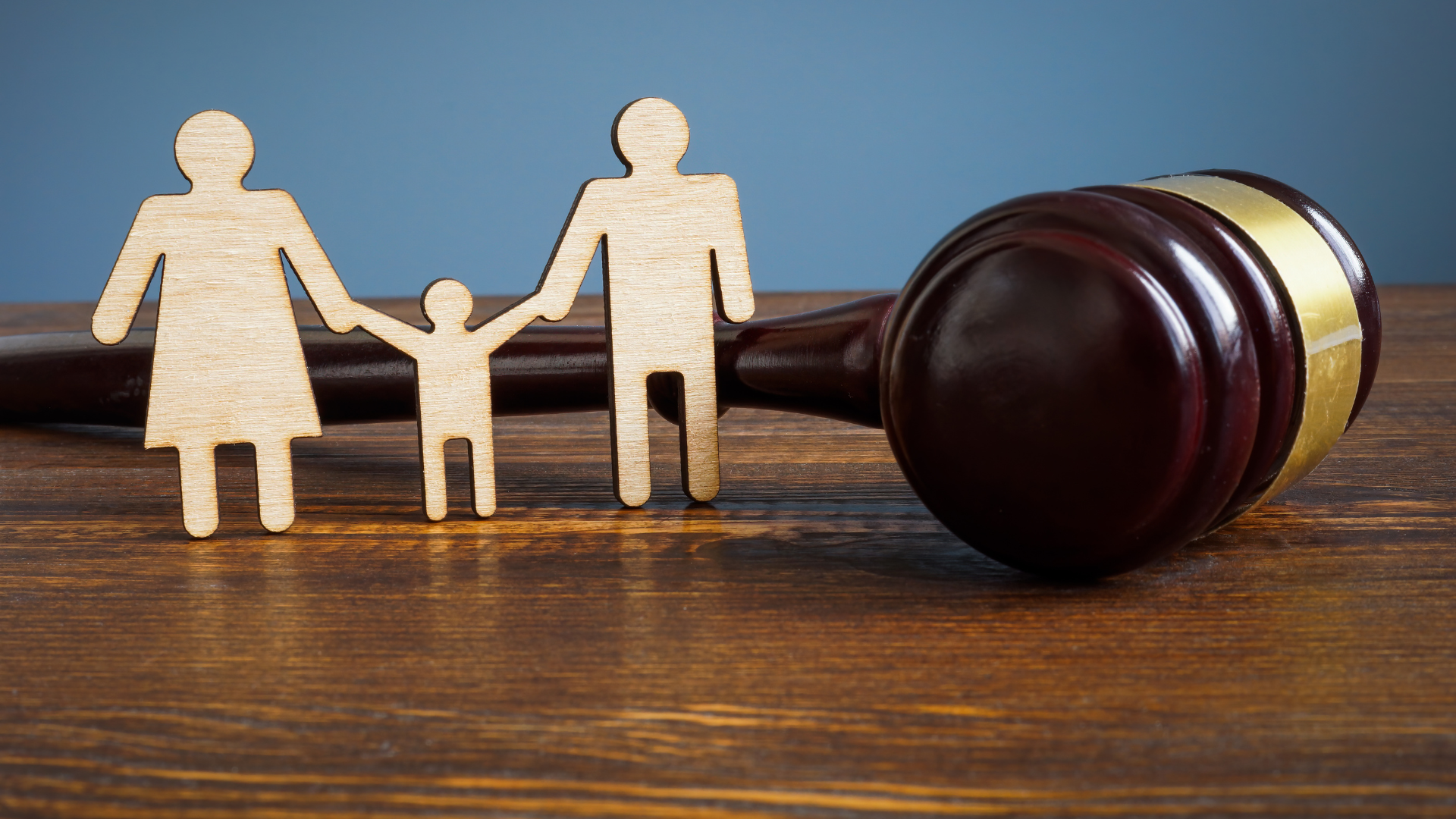 A wooden family is sitting next to a wooden judge 's gavel on a wooden table.