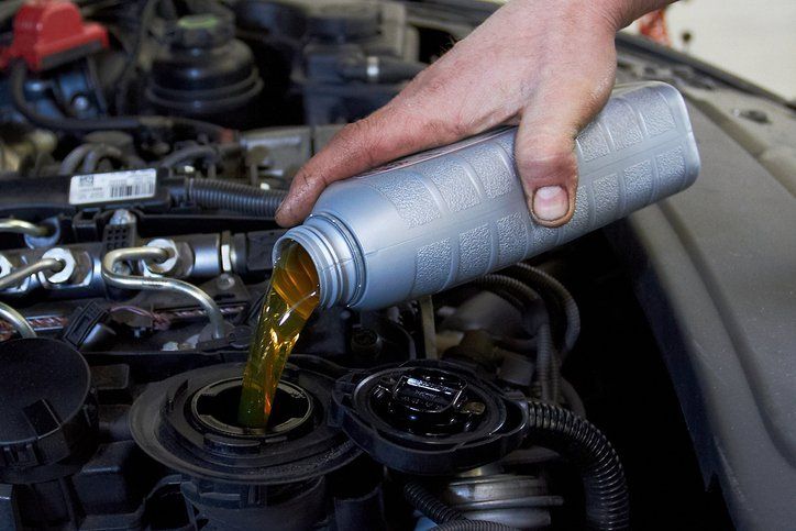 A person is pouring oil into a car engine.