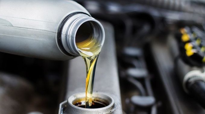 A bottle of oil is being poured into a car engine.