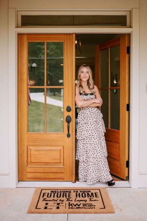 A woman is sitting at a desk with a laptop and a vase of flowers.