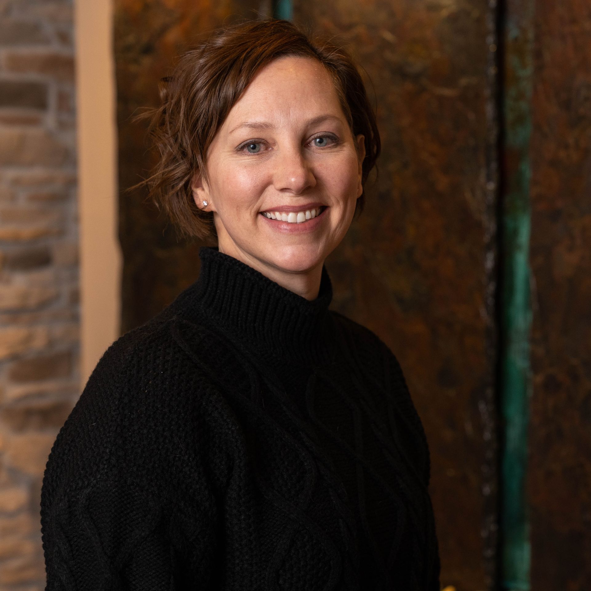 A woman in a black sweater is smiling for the camera.