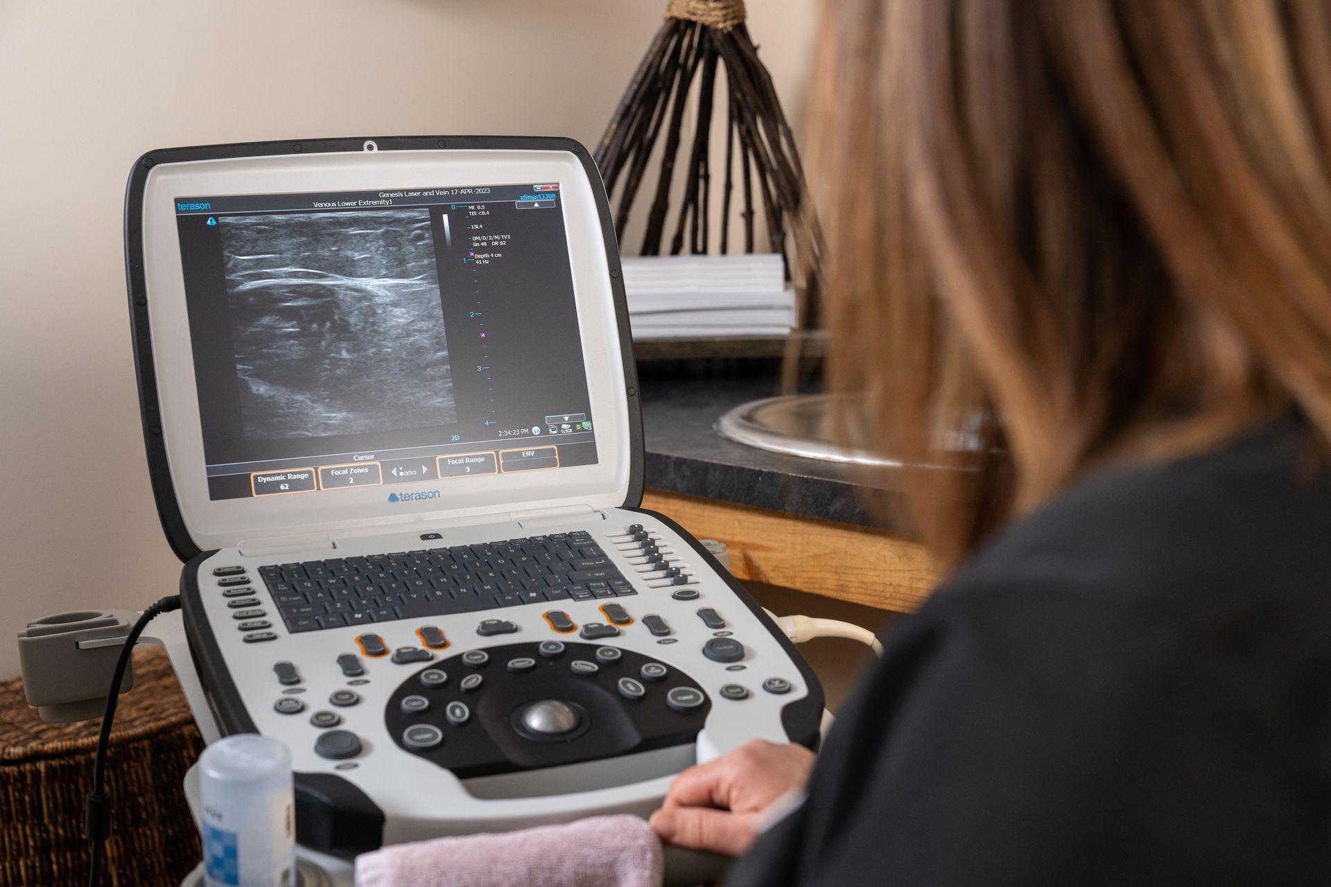 A woman is using an ultrasound machine on a table.