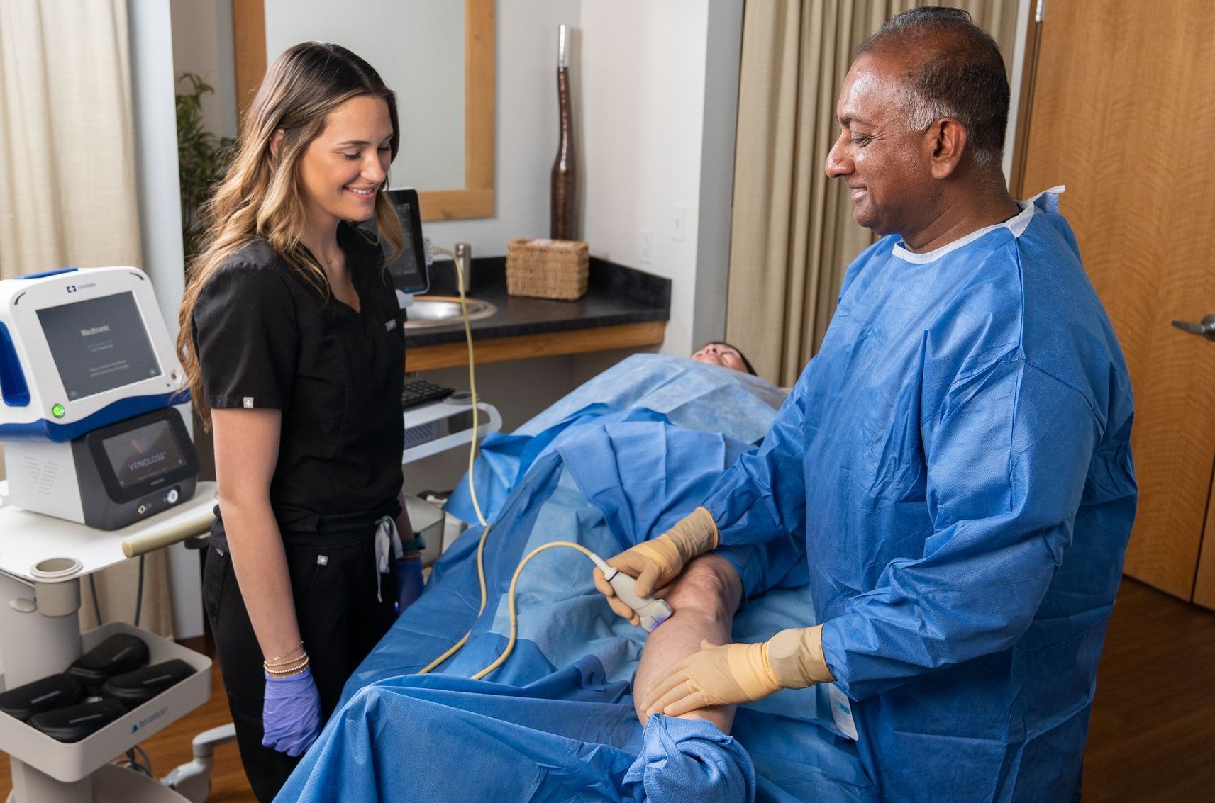 A surgeon and a nurse are talking to a patient in an operating room.