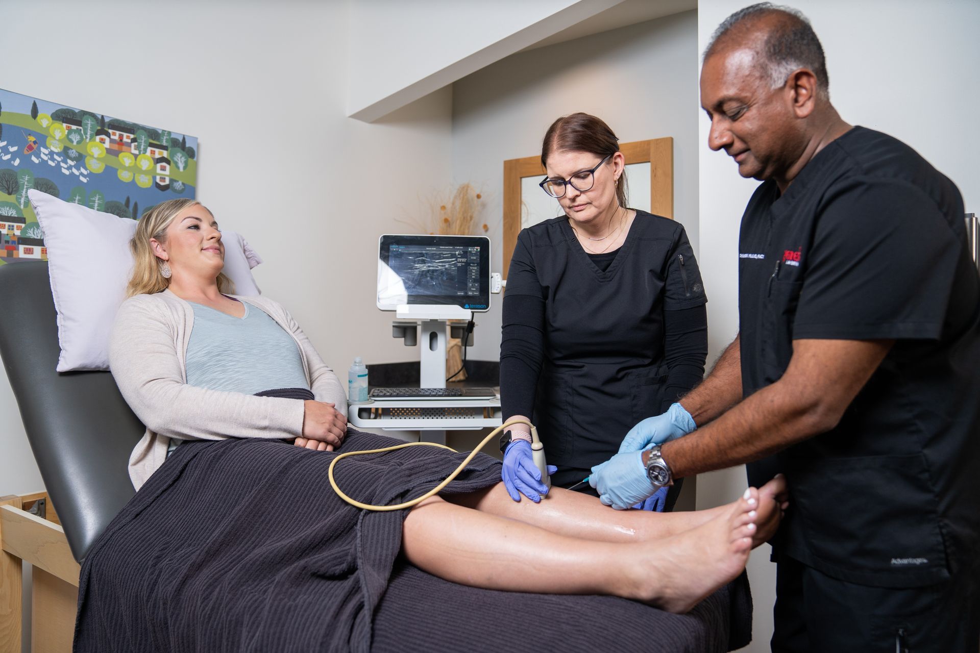 A woman is laying in a hospital bed while a doctor examines her leg.