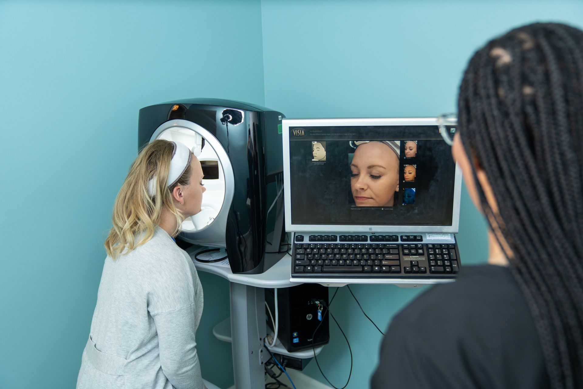 A woman is looking at her face on a computer screen.