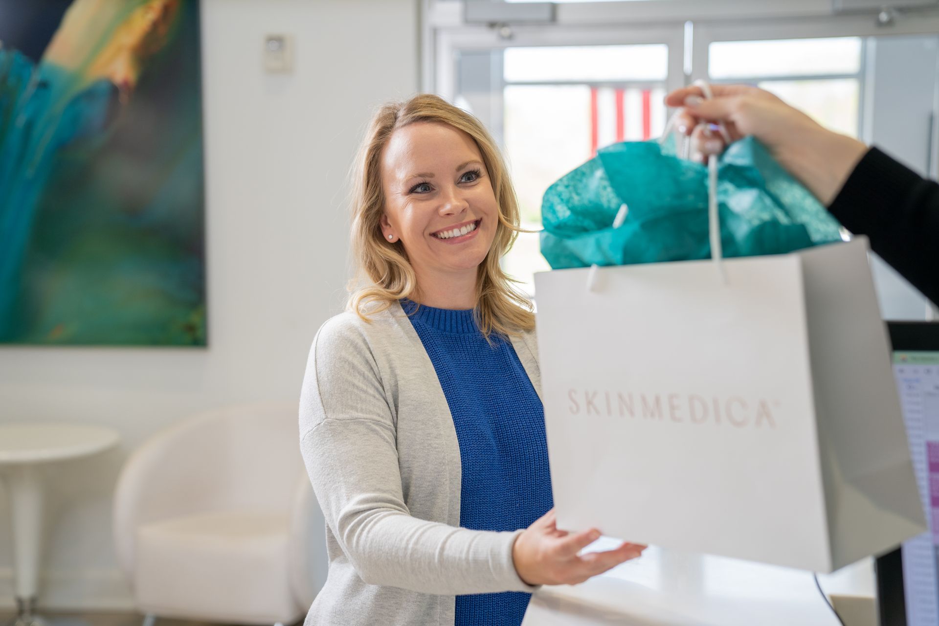 A woman is receiving a gift bag from another woman.