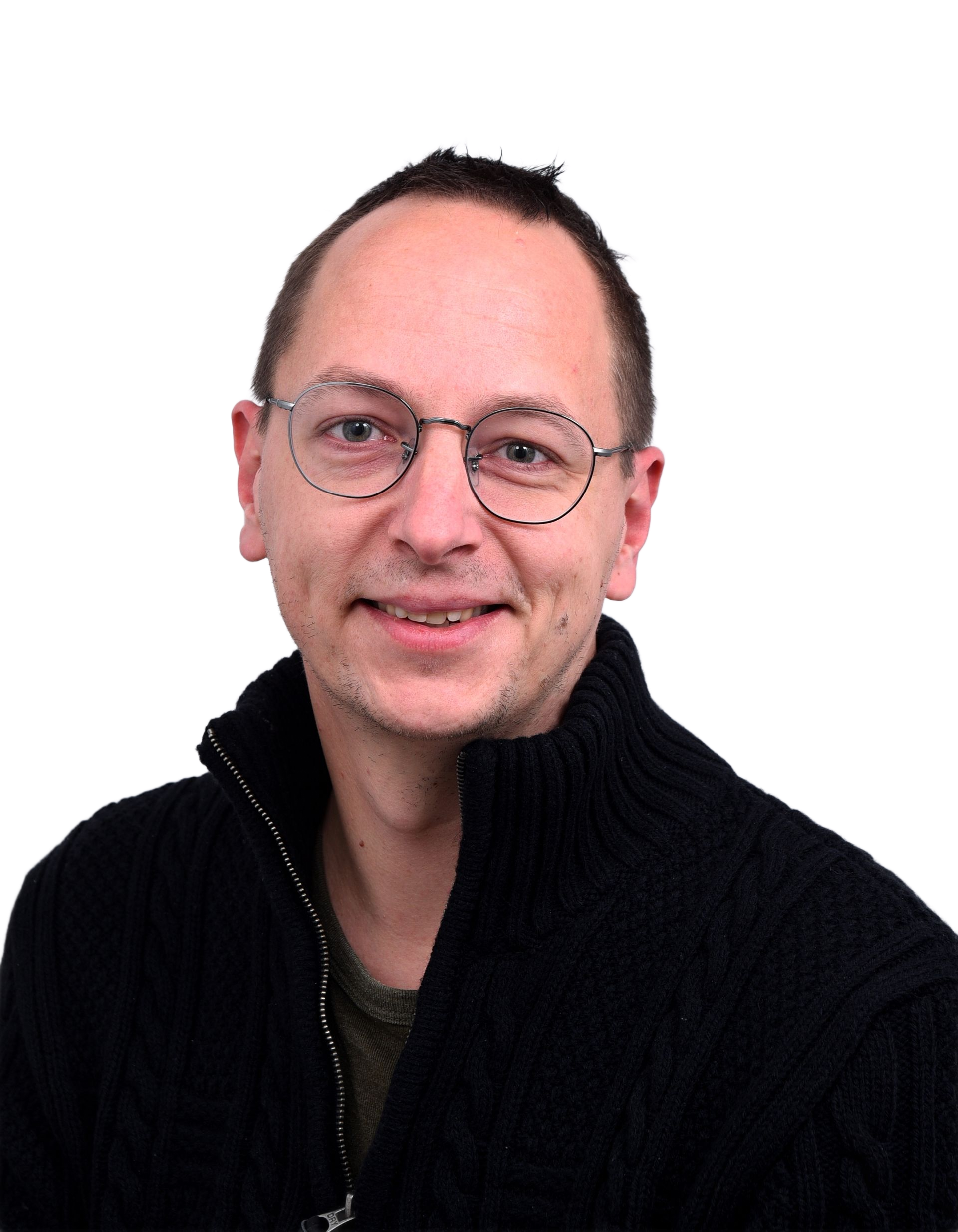 Een man met een bril en een zwarte trui lacht naar de camera