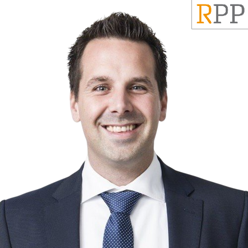 Een man in pak en stropdas lacht voor een rpp-logo