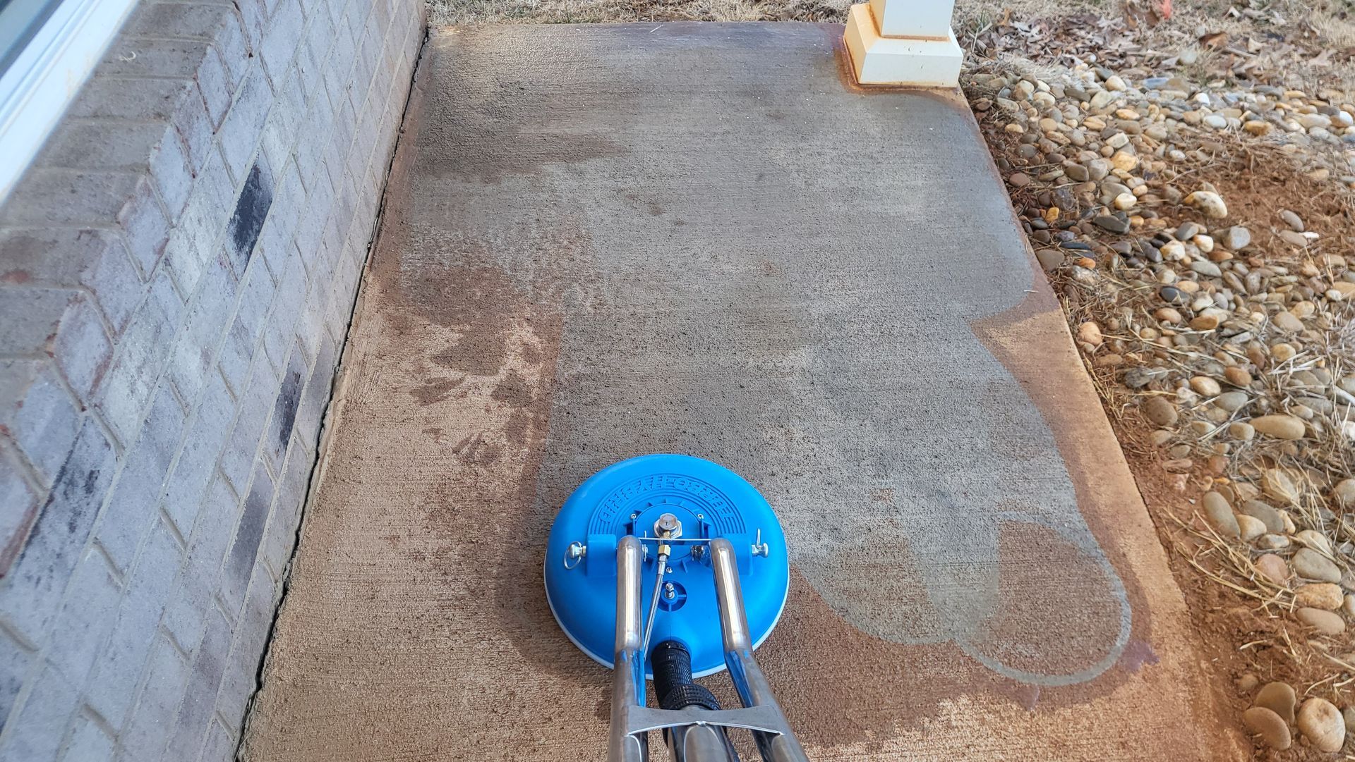 Two-story beige house with a stone front, black roof, and two-car garage. A concrete driveway leads to the house.