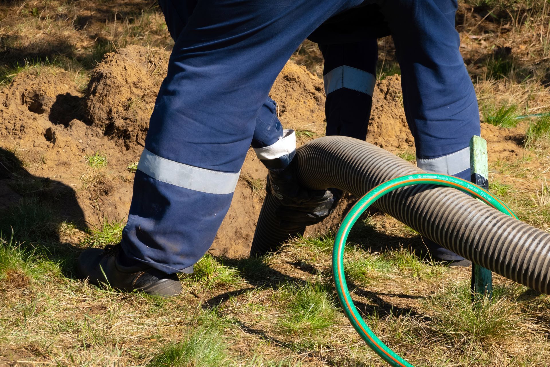 Close-up of a worker holding a pipe, performing local septic pumping services.