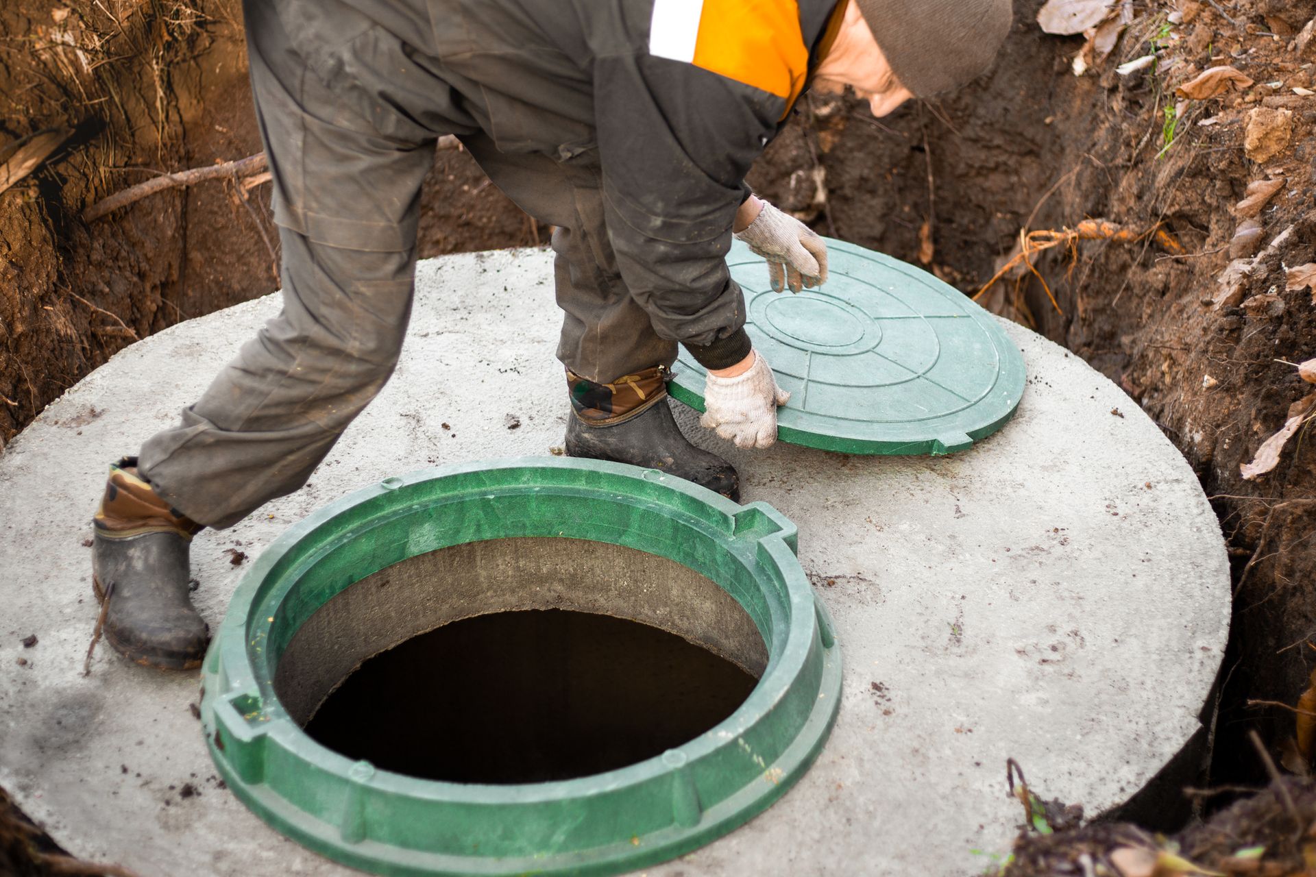 The utility worker opened the septic hatch for sewer maintenance and waste removal.