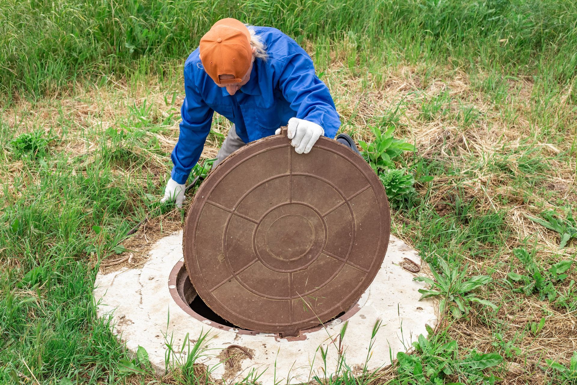 A worker checks a plumbing well. He is performing maintenance and cleaning of septic wells.