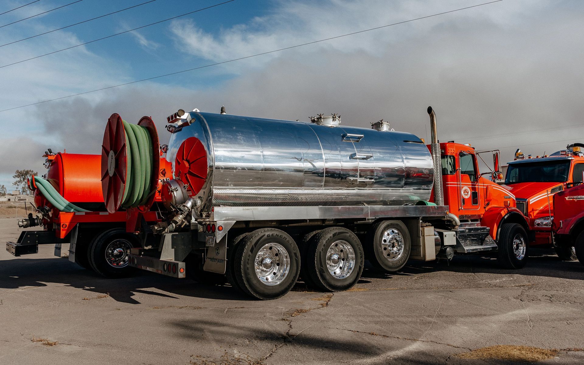 Large vacuum truck outside a warehouse under cloudy skies.