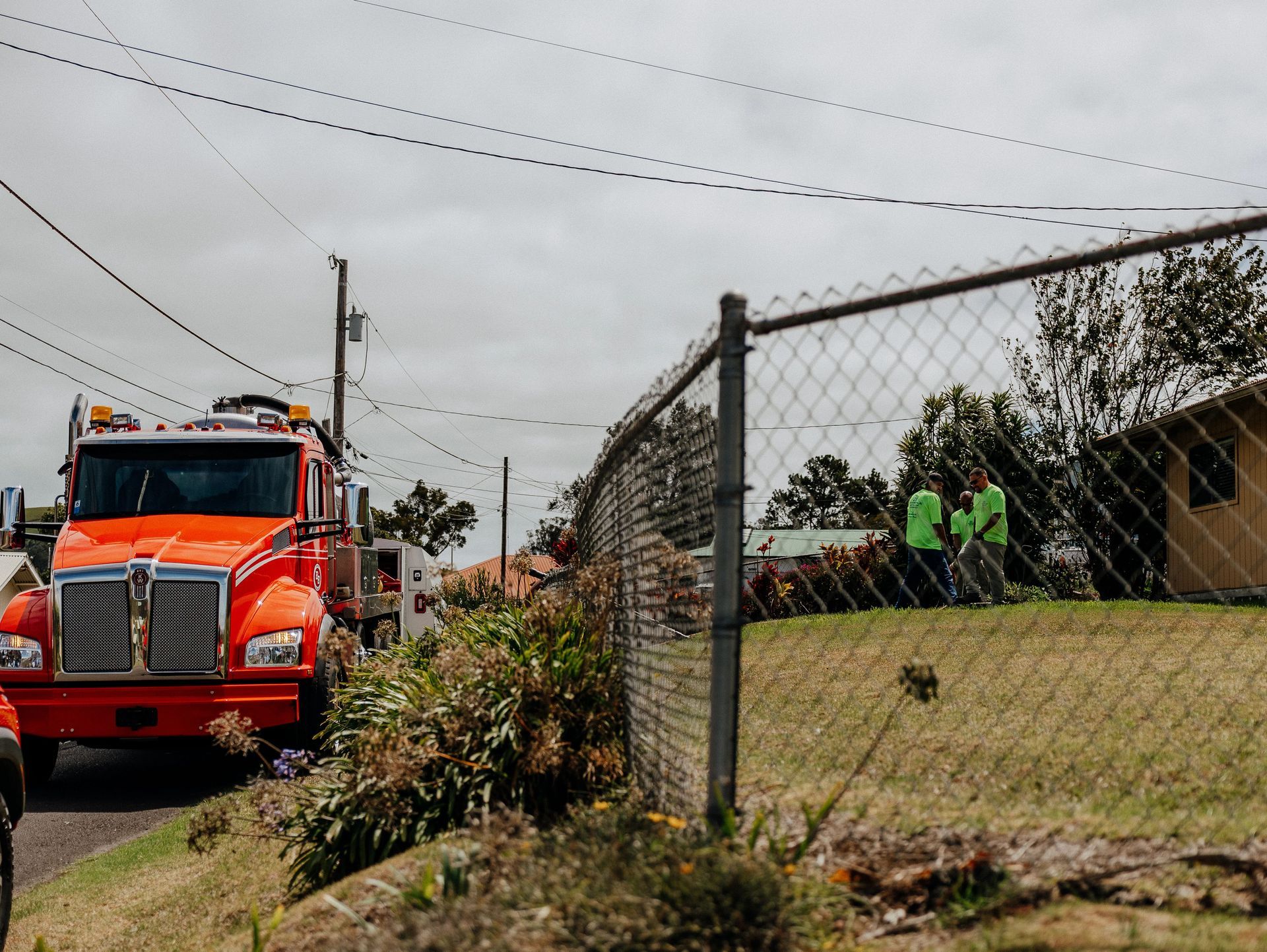 Technician preparing hoses next to a home with lush tropical landscaping.