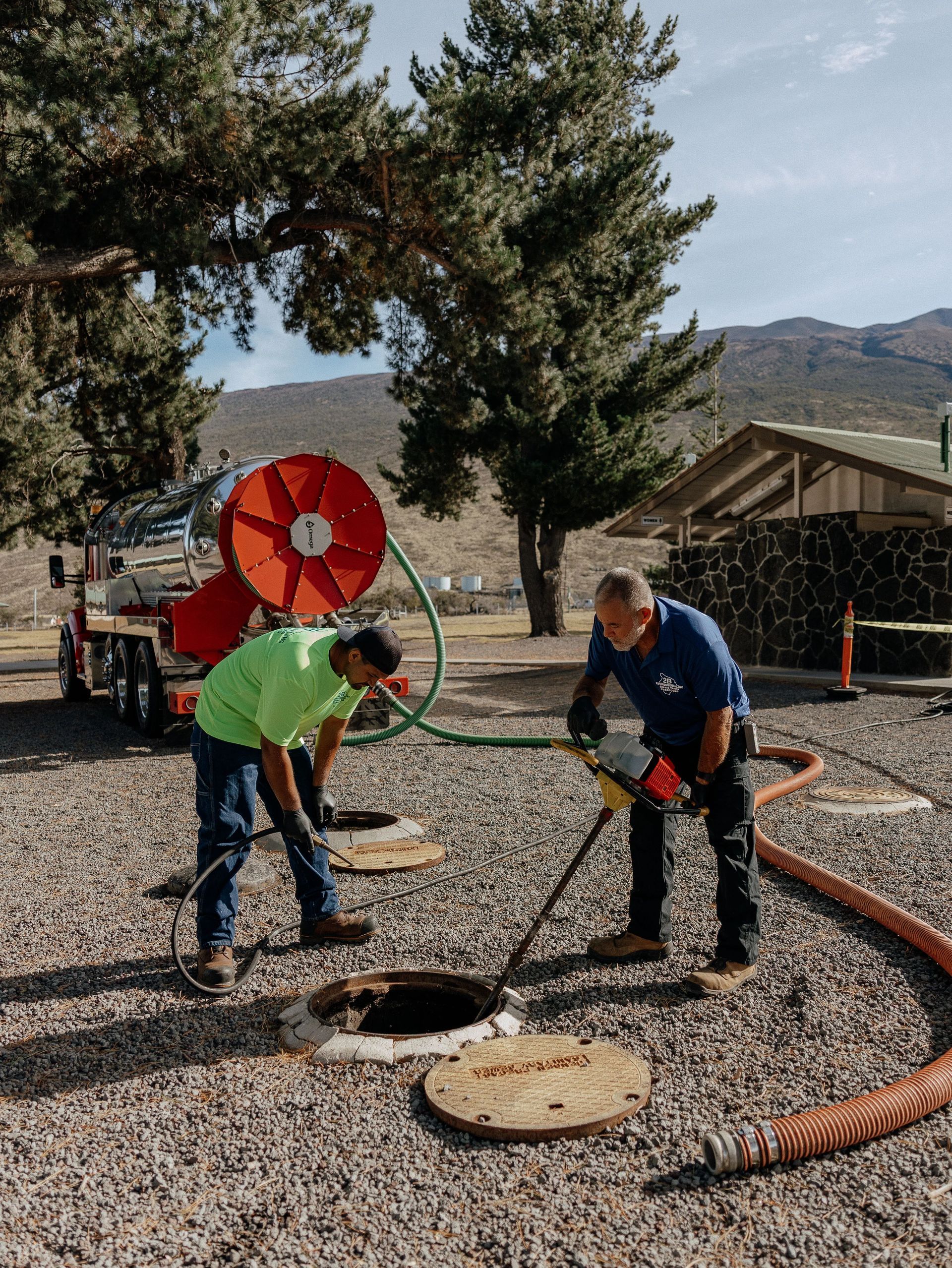 Jetting hose entering a concrete storm drain during light rain.
