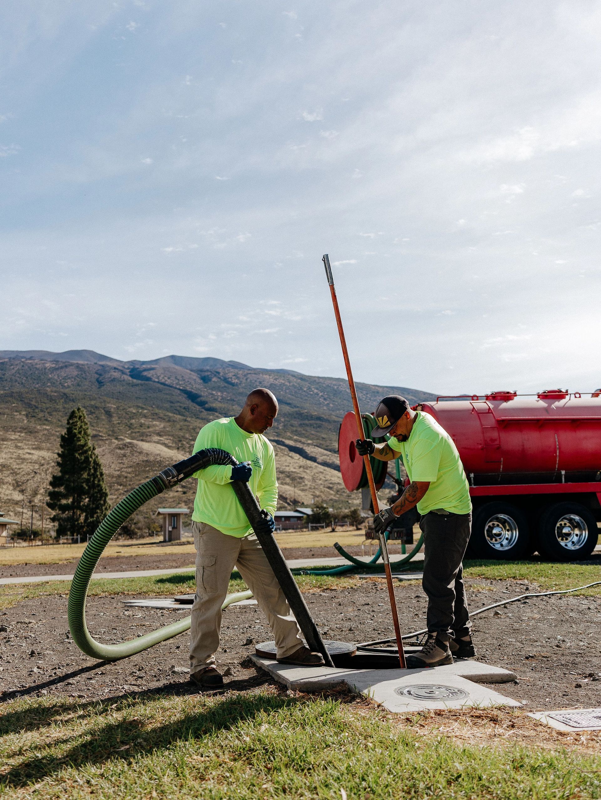 A crew member safely accessing an old cesspool cover on a rural homestead.
