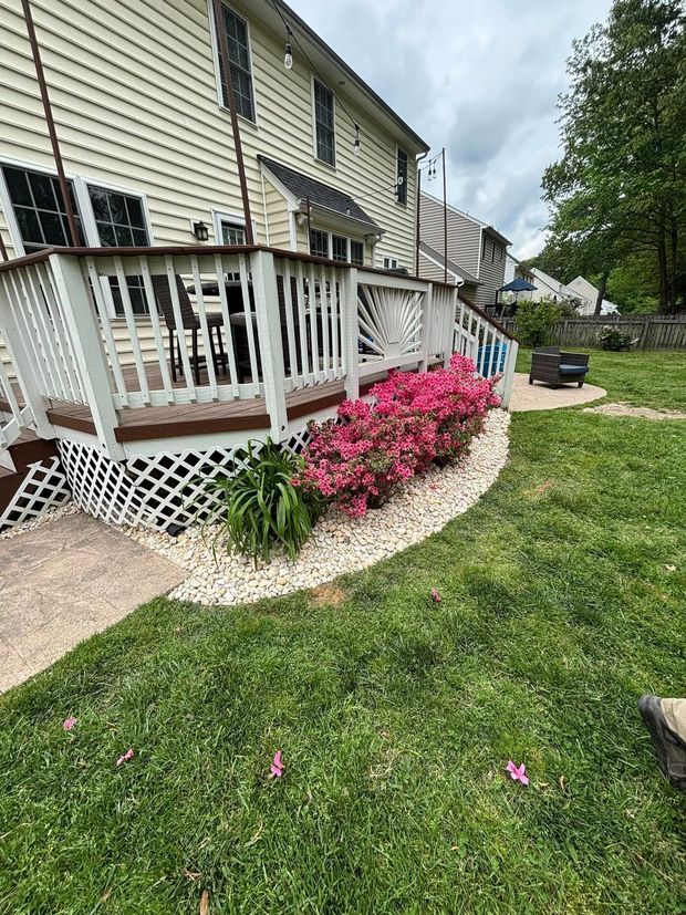 A large white house with a large deck and a lush green yard.