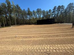 A large dirt field with trees in the background