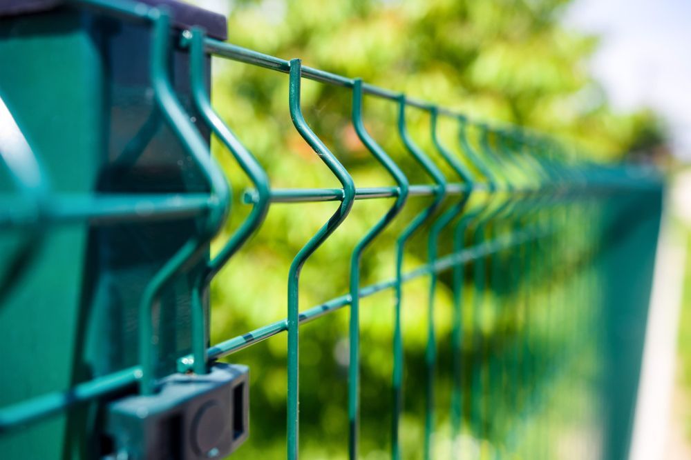 Green Metal Fence With a Blurred Green Background — Keith Dellit Rural Fencing in Yandina Creek, QLD